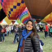 Harini standing in front of several hot-air balloons